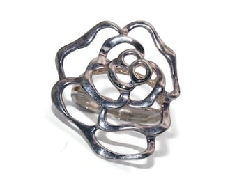 May include: A silver ring with a rose design. The ring is made of a single piece of metal that is shaped into a rose.
