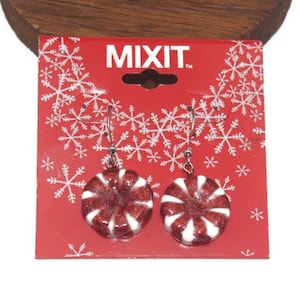 Könnte beinhalten: Ein Paar rote und weiße Pfefferminzbonbon-Ohrringe mit silbernen Haken. Die Ohrringe befinden sich auf einer roten Karte mit weißen Schneeflocken und dem aufgedruckten Wort "MIXIT".