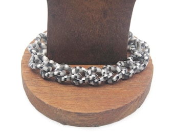 May include: A silver chain bracelet with black and white checkered pattern links.