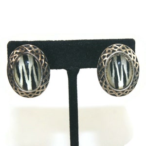 Tonalità argento vintage con clip a cupola ovale in resina bianca e nera sugli orecchini.