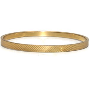 May include: A gold bangle bracelet with a textured, ridged design.