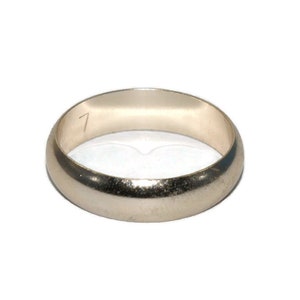 Könnte beinhalten: Ein silberfarbener Ring mit einem abgerundeten Band. Der Ring hat eine glatte, polierte Oberfläche und eine kleine Zahl "7" auf der Innenseite. Der Ring ist vor einem weißen Hintergrund platziert.