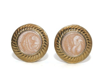 May include: A pair of gold-tone earrings with a swirl design in a light pink color.