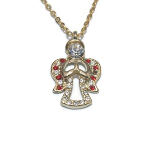May include: Gold-toned angel pendant necklace with a clear crystal head and body, red and clear crystal accents on the wings. The necklace has a delicate gold chain and is set against a white background.