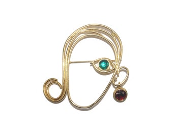Vintage Gold Tone Abstract Face Brooch with Green Rhinestone Eye and Red Rhinestone Earring.