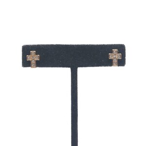 May include: A pair of gold cross earrings with small clear cubic zirconia stones.
