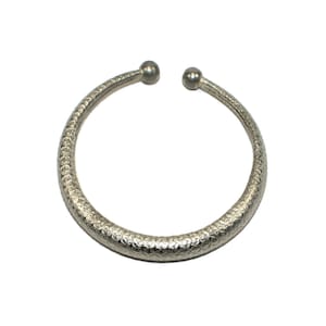 May include: A silver bangle bracelet with a textured surface.