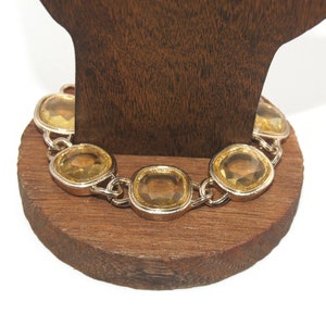 Pode incluir: Um bracelete de corrente de ouro com pedras grandes, transparentes e facetadas de cor amarela.