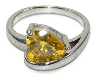 May include: A silver ring with a yellow heart-shaped gemstone.