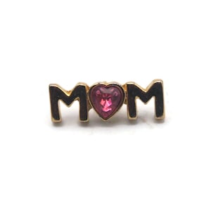 May include: Gold-tone pin with the word "MOM" in black letters and a pink heart-shaped rhinestone in the center.