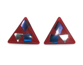 May include: A pair of red triangular earrings with blue and silver geometric shapes.