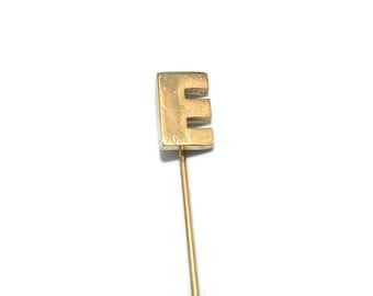 Broche vintage dourado com monograma da letra "E", ideal para chapéus ou gravatas.