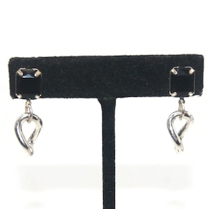 May include: A pair of silver earrings with black square-shaped stones and a twisted heart dangle.