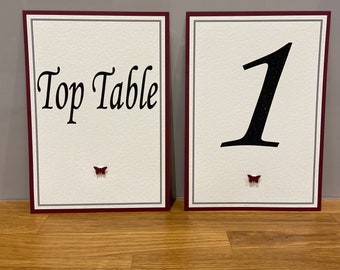 Nombres o números de mesa para bodas. Con detalle de corazón o mariposa en colores lisos o brillantes a elegir y fondo a juego. 'Emily'