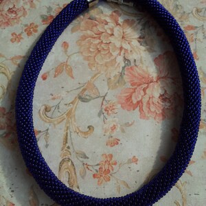 May include: A dark blue beaded necklace with silver clasps. The necklace is made of small, round beads and is about 18 inches long.