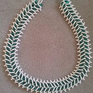 May include: A white and green beaded necklace with a zig-zag pattern.