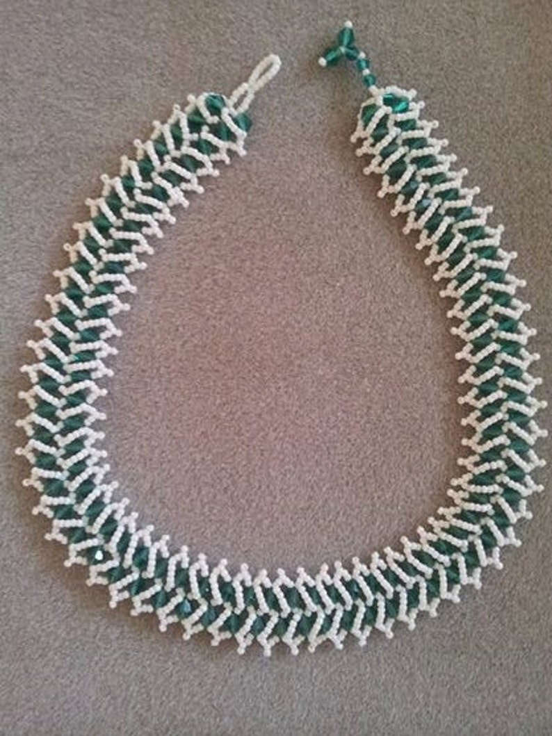 May include: A white and green beaded necklace with a zig-zag pattern.