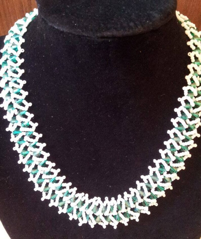 May include: A white and green beaded necklace with a geometric pattern. The necklace is made of small, faceted beads that are strung together in a repeating pattern.