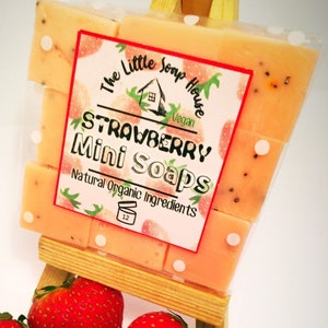 May include: A pack of 12 small, pink, strawberry-scented soaps with white polka dots. The label reads "The Little Soap House Vegan Strawberry Mini Soaps Natural Organic Ingredients".