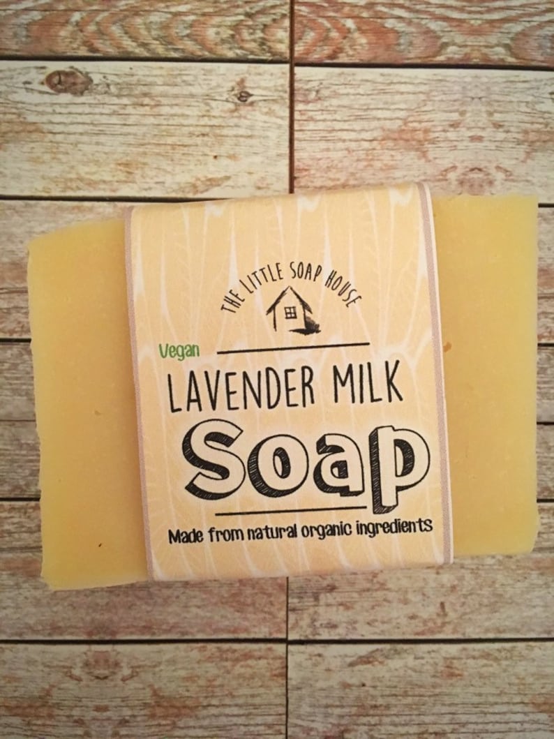 May include: A bar of yellow soap with a label that reads "The Little Soap House" and "Lavender Milk Soap" in black text. The label also says "Vegan" and "Made from natural organic ingredients".