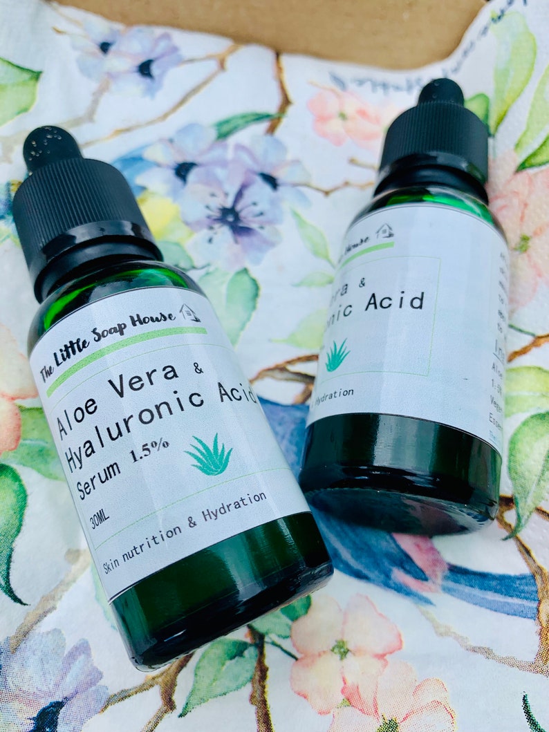 Puede incluir: Dos botellas de vidrio verde con goteros que contienen sueros para el cuidado de la piel. La botella de la izquierda est&aacute; etiquetada "The Little Soap House Aloe Vera & Hyaluronic Acid Serum 1.5% 30ML Skin nutrition & Hydration". La botella de la derecha est&aacute; etiquetada "Vera & nic Acid Hydration".