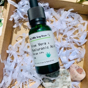 Puede incluir: Una botella de vidrio verde con un gotero negro, etiquetada "The Little Soap House Aloe Vera & Hyaluronic Acid Serum 1.5% 30ML Skin nutrition & Hydration".