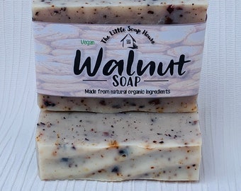 May include: Two bars of handmade walnut soap. The soap is light beige with dark brown flecks and a paper band that reads "The Little Soap House" and "Walnut SOAP". The soap is made from natural organic ingredients and is vegan.