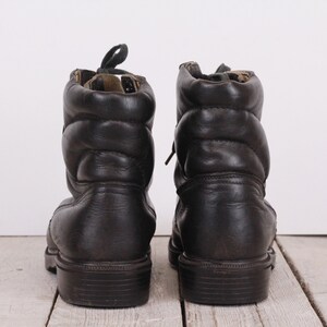 May include: A pair of black leather boots with laces. The boots have a padded ankle and a thick sole.