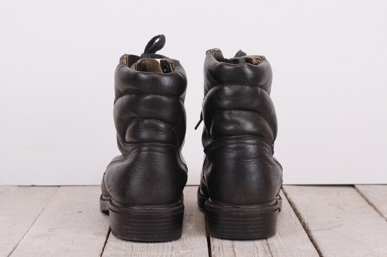 May include: A pair of black leather boots with laces. The boots have a padded ankle and a thick sole.