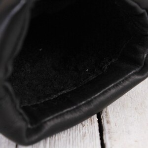 Peut inclure: Gros plan de l'int&eacute;rieur d'un gant en cuir noir. Le gant est fait de cuir noir lisse et brillant avec une doublure douce et noire. Les coutures sont visibles sur les bords.