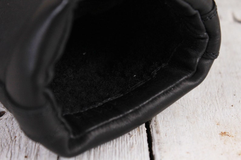 Peut inclure: Gros plan de l'int&eacute;rieur d'un gant en cuir noir. Le gant est fait de cuir noir lisse et brillant avec une doublure douce et noire. Les coutures sont visibles sur les bords.