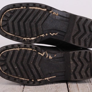 May include: Close-up of the bottom of a pair of black leather boots with a textured rubber sole.