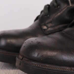 May include: A pair of black leather boots with laces. The boots have a worn look and are slightly scuffed.