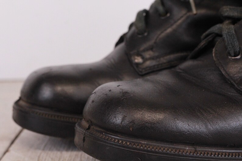 May include: A pair of black leather boots with laces. The boots have a worn look and are slightly scuffed.