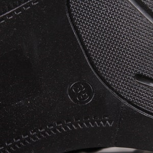 Peut inclure: Gros plan d'une semelle de chaussure noire avec un motif textur&eacute; et la taille 36 en relief dans un cercle. La semelle a un motif en forme de losange et un bord cousu.