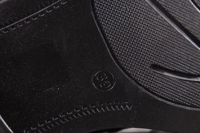 Peut inclure: Gros plan d'une semelle de chaussure noire avec un motif textur&eacute; et la taille 36 en relief dans un cercle. La semelle a un motif en forme de losange et un bord cousu.