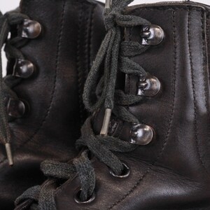 May include: A pair of black leather lace-up boots with dark grey laces and silver metal eyelets.