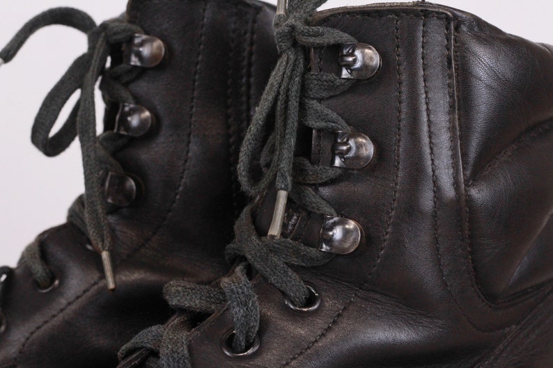 May include: A pair of black leather lace-up boots with dark grey laces and silver metal eyelets.