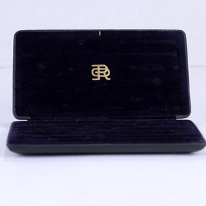 May include: A black velvet-lined box with a gold "BR" logo on the lid. The box is open and the interior is lined with black velvet.