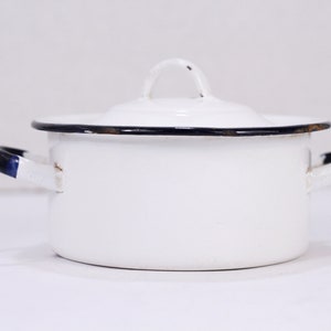 May include: White enamel pot with black trim and two handles. The pot has a lid with a small handle.