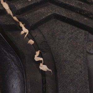 May include: Close-up of the bottom of a black leather boot with a rubber sole. The sole has the numbers "36" and "38" printed on it.