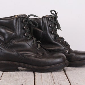 May include: A pair of black leather lace-up boots with a chunky heel. The boots have a slightly distressed look and are made of a durable material.