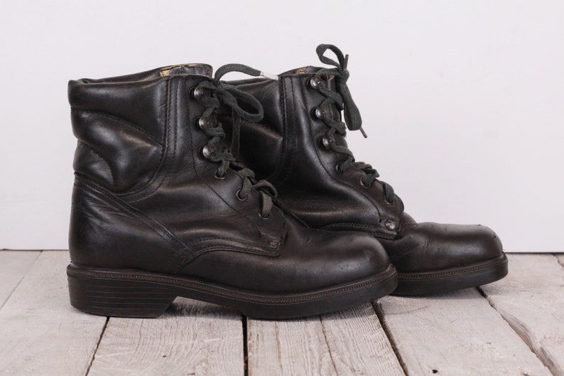 May include: A pair of black leather lace-up boots with a chunky heel. The boots have a slightly distressed look and are made of a durable material.