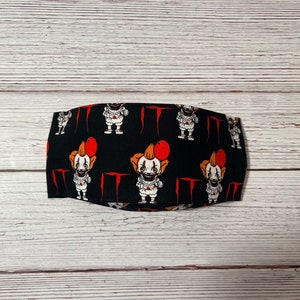 May include: Black fabric face mask with a repeating pattern of a clown holding a red balloon and the word "IT" in red.