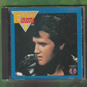 May include: Elvis' Gold Records Volume 5 CD in a jewel case. The album cover features a portrait of Elvis Presley against a dark background with a blue border. The RCA logo is visible in the lower right corner.