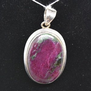 May include: A silver pendant with a large oval-shaped pink and green gemstone.