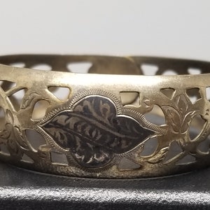 May include: A silver filigree bracelet with a floral design. The bracelet is open and has a delicate, intricate pattern.