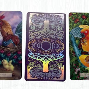 May include: Three tarot cards with colorful illustrations. The first card shows a rooster and hen with chicks, and the text "Ten of Cups". The second card has a purple background with a gold and silver tree design. The third card shows two parrots with cups, and the text "Three of Cups".