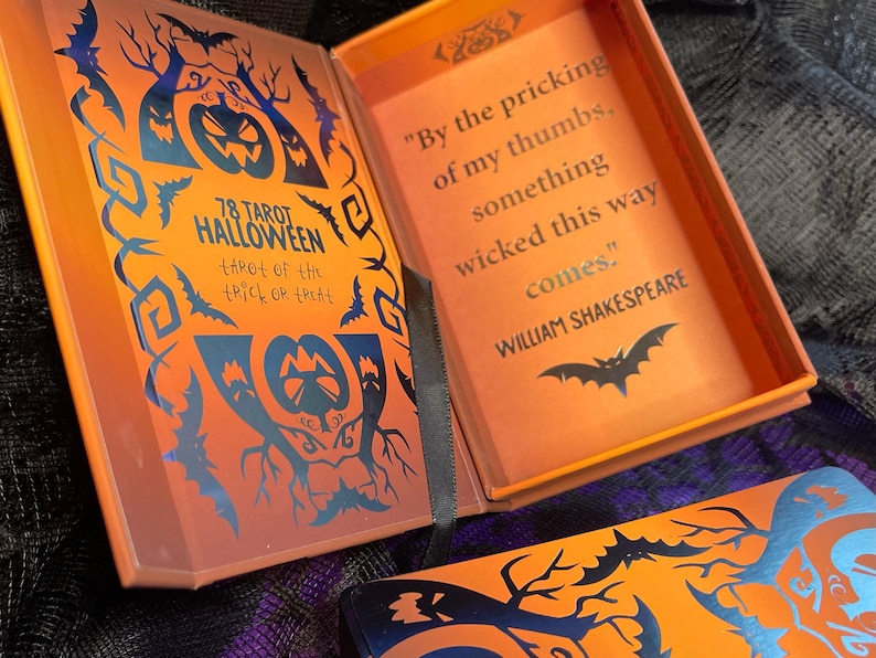 K&ouml;nnte beinhalten: Eine Schachtel f&uuml;r ein 78 Karten Tarot-Deck mit Halloween-Thema. Die Schachtel ist orange mit schwarzen Flederm&auml;usen und einem K&uuml;rbis-Design. Der Text auf der Schachtel lautet "78 Tarot Halloween Tarot of the Trick or Treat". Die Innenseite der Schachtel ist orange mit einer schwarzen Fledermaus und einem Zitat von William Shakespeare: "By the pricking of my thumbs, something wicked this way comes."
