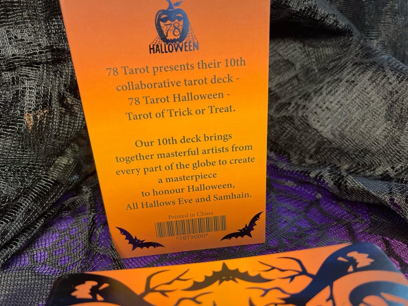 K&ouml;nnte beinhalten: Die R&uuml;ckseite einer Tarot-Kartendeck-Box mit orangefarbenem Hintergrund und schwarzem Text. Der Text lautet "78 Tarot pr&auml;sentiert sein 10. gemeinsames Tarot-Deck - 78 Tarot Halloween - Tarot von S&uuml;&szlig;es oder Saures. Unser 10. Deck vereint meisterhafte K&uuml;nstler aus aller Welt, um ein Meisterwerk zu schaffen, um Halloween, Allerheiligen und Samhain zu ehren. Gedruckt in China 7879000".